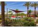 Resort-style pool area with lounge chairs, palm trees and shade sails for ultimate relaxation at 27380 N 128Th Ln, Peoria, AZ 85383