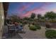 Backyard featuring gravel landscaping, patio area with seating, and lush plants at dusk at 36042 N Desert Tea Dr, Queen Creek, AZ 85140