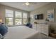 Bright bedroom featuring a comfortable bed, a dresser with TV, and large windows showcasing outdoor views at 36042 N Desert Tea Dr, Queen Creek, AZ 85140