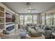 Inviting living room with a cozy fireplace, built-in shelves, ceiling fan, and large windows for natural light at 36042 N Desert Tea Dr, Queen Creek, AZ 85140