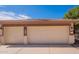 Three-car garage with neutral colored doors and trim under a deep blue sky at 3665 E Thames Way, San Tan Valley, AZ 85140