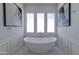Modern bathroom featuring a standalone tub, marble floors, wainscoting and natural light from three windows at 3813 N 37Th St, Phoenix, AZ 85018