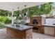 Outdoor kitchen area with a built-in brick pizza oven, a grill, and a sink for outdoor cooking at 3817 E Highland Ave, Phoenix, AZ 85018