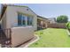 Backyard view featuring a covered patio with outdoor seating, grassy area, and desert landscaping at 3892 E Harrison St, Gilbert, AZ 85295