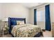 Comfortable bedroom with a large blue headboard, patterned bedding, and blue curtains at 4132 N 42Nd St, Phoenix, AZ 85018