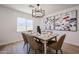 Staged dining room boasts modern art, light fixture, wood floors, and stylish seating, enhancing the space's appeal at 4234 E Winnetka Dr, Phoenix, AZ 85044