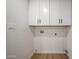 Bright laundry area with white cabinets and wood-look floors, offering storage and functionality at 4234 E Winnetka Dr, Phoenix, AZ 85044
