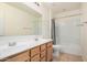 Well-lit bathroom with double sinks, wooden cabinets, large mirror, and shower with tub at 44157 W Palo Amarillo Rd, Maricopa, AZ 85138