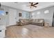 Spacious living room featuring wood-look tile, neutral paint, updated fan and a sectional sofa at 5741 W Warner St, Phoenix, AZ 85043