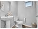 Bright powder room with a pedestal sink, white toilet, wood-look floors, and a window at 5741 W Warner St, Phoenix, AZ 85043