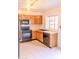 Cozy kitchen featuring wooden cabinetry, black appliances, and a window overlooking the sink at 921 W University Dr # 1191, Mesa, AZ 85201
