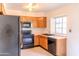 A functional kitchen featuring wood cabinets and black appliances, illuminated by a light fixture at 921 W University Dr # 1191, Mesa, AZ 85201