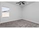 Empty bedroom showcasing plush gray carpet, a modern ceiling fan, and a window with natural light at 9310 W Washington St, Tolleson, AZ 85353