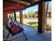 Tranquil covered patio with swing and views of the pool, lush greenery, and scenic desert landscape at 9607 E Mckellips Rd, Mesa, AZ 85207