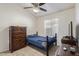 Well-lit bedroom featuring warm tile flooring, a decorative ceiling fan, and matching furniture at 10465 W Windsor Blvd, Glendale, AZ 85307