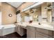 Bright bathroom featuring dual sinks, large mirror, soaking tub, and stylish neutral color palette at 11807 E Clinton St, Scottsdale, AZ 85259