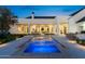 Backyard view of a pool and spa with lighting, manicured lawn, and covered patio space at 12240 N 98Th St, Scottsdale, AZ 85260