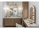 Vanity area with wood cabinets, marble countertops, Hollywood makeup mirror, and decorative wall sconces at 12240 N 98Th St, Scottsdale, AZ 85260