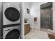 Modern bathroom with a stacked washer/dryer, stylish vanity, and tiled shower for convenience and luxury at 12240 N 98Th St, Scottsdale, AZ 85260