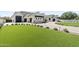 A lovely home boasts a large green lawn, exterior lights, a manicured landscape, and a black four car garage at 12240 N 98Th St, Scottsdale, AZ 85260