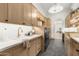Well-organized laundry room with wood cabinets, quartz countertops, modern appliances, and black herringbone floors at 12240 N 98Th St, Scottsdale, AZ 85260