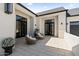 A beautiful stone patio is furnished with cushioned chairs and black framed glass doors at 12240 N 98Th St, Scottsdale, AZ 85260