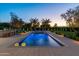 Backyard pool with water features, travertine tile surround, basketball court, and lush landscaping at dusk at 12240 N 98Th St, Scottsdale, AZ 85260