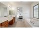 Bright bathroom featuring tile floors, soaking tub, and double vanity at 15469 W Dreyfus St, Surprise, AZ 85379