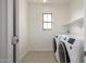 Bright laundry room features tile floor, white washer and dryer, plus storage shelves at 15469 W Dreyfus St, Surprise, AZ 85379
