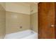 This bathroom features a white bathtub, tiled walls, and a wooden door at 1654 E 2Nd St, Mesa, AZ 85203