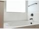 Close-up of a modern bathtub with a dark faucet and bright window at 18813 W Solano Dr, Litchfield Park, AZ 85340