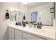 Double sink bathroom with a light countertop, mirror, and white cabinetry at 18813 W Solano Dr, Litchfield Park, AZ 85340