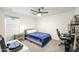 A modern bedroom with a bed, ceiling fan and desk area, illuminated by natural light at 18813 W Solano Dr, Litchfield Park, AZ 85340