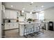 White kitchen features an island with seating, stainless steel appliances, and lots of natural light at 18813 W Solano Dr, Litchfield Park, AZ 85340