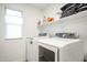 Bright laundry room with modern washer, dryer, window, and shelf at 18813 W Solano Dr, Litchfield Park, AZ 85340
