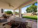 Covered back porch with seating, table and view of the pool, hardscape and green grass at 20404 N 28Th Pl, Phoenix, AZ 85050