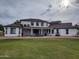 View of the back of a large white home surrounded by green grass and with a red rock perimeter at 2060 E Quartz St, Mesa, AZ 85213