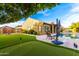Beautiful backyard featuring a putting green, pool, and patio area, ideal for recreation and relaxation at 21401 E Russet Rd, Queen Creek, AZ 85142