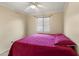 Bedroom with a ceiling fan, window with blinds, and bed with a red quilt and pillows at 2201 W Wethersfield Rd, Phoenix, AZ 85029