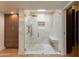 Modern tiled shower with glass door, bench, and storage in a light and airy bathroom at 2737 E Arizona Biltmore Cir # 8, Phoenix, AZ 85016