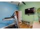 Well-lit exercise room with blue and green walls, television, and a modern treadmill at 3416 E Squawbush Pl, Phoenix, AZ 85044