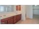 Bathroom featuring double sinks, tile flooring, wood cabinets, and a walk-in closet at 42468 W Palmyra Ct, Maricopa, AZ 85138