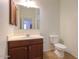 Clean bathroom with wood vanity, sink, toilet, and large mirror at 42468 W Palmyra Ct, Maricopa, AZ 85138
