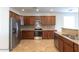 Well-equipped kitchen with stainless steel appliances, backsplash and dark wood cabinets at 42468 W Palmyra Ct, Maricopa, AZ 85138