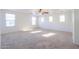 Large, bright carpeted living area with multiple windows and ceiling fan at 42468 W Palmyra Ct, Maricopa, AZ 85138