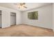 Bedroom features neutral carpet, a closet, a ceiling fan, and a view to the backyard at 6602 W Ironwood Dr, Glendale, AZ 85302
