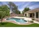 Backyard featuring a pool, lush landscaping, artificial grass, and an outdoor kitchen at 7214 E Rustling Pass, Scottsdale, AZ 85255