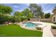 Backyard showcasing a lagoon style pool, lush landscaping, and an outdoor kitchen at 7214 E Rustling Pass, Scottsdale, AZ 85255
