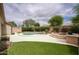 Backyard featuring a lagoon style pool, a built-in fire pit, and artificial grass at 7214 E Rustling Pass, Scottsdale, AZ 85255
