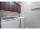 Functional laundry room featuring updated machines, overhead cabinets for storage, and a bright, clean space at 809 W Coles Rd, Phoenix, AZ 85041